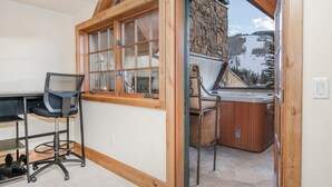 A room with a wooden desk, a chair, a hot tub, and a view of a snowy mountain. - Luxury condo only 1 block to Bridge St. & slopes. Private hot tub free parking!! (Vail)