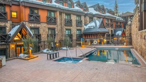 A hotel courtyard with a swimming pool, stone walls, and wooden buildings. - Luxury condo only 1 block to Bridge St. & slopes. Private hot tub free parking!! (Vail)