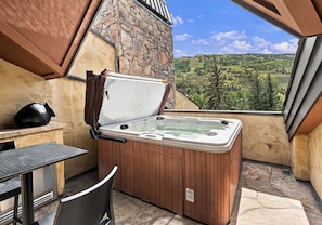 Ein Whirlpool mit Steinwand und Blick auf eine Berglandschaft.