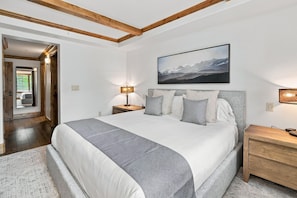 Ein Schlafzimmer mit einem großen Bett, einem Nachttisch, einer Lampe und einem Gemälde an der Wand.