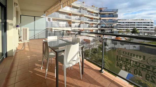 A balcony with a glass table and chairs, overlooking a residential building with multiple balconies. - Modern apartment only 300 m. from the beach  (Cambrils)
