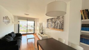A modern living room with a black sofa, a dining table, and a large window. - Modern apartment only 300 m. from the beach  (Cambrils)