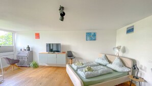 Une chambre à coucher moderne avec un lit, une table de chevet, une lampe et un téléviseur posé sur un meuble.