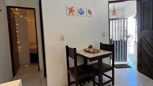 A dining area with a table and chairs, a small potted plant, and three framed pictures on the wall. - Cores da Pipa flats (Tibau do Sul)
