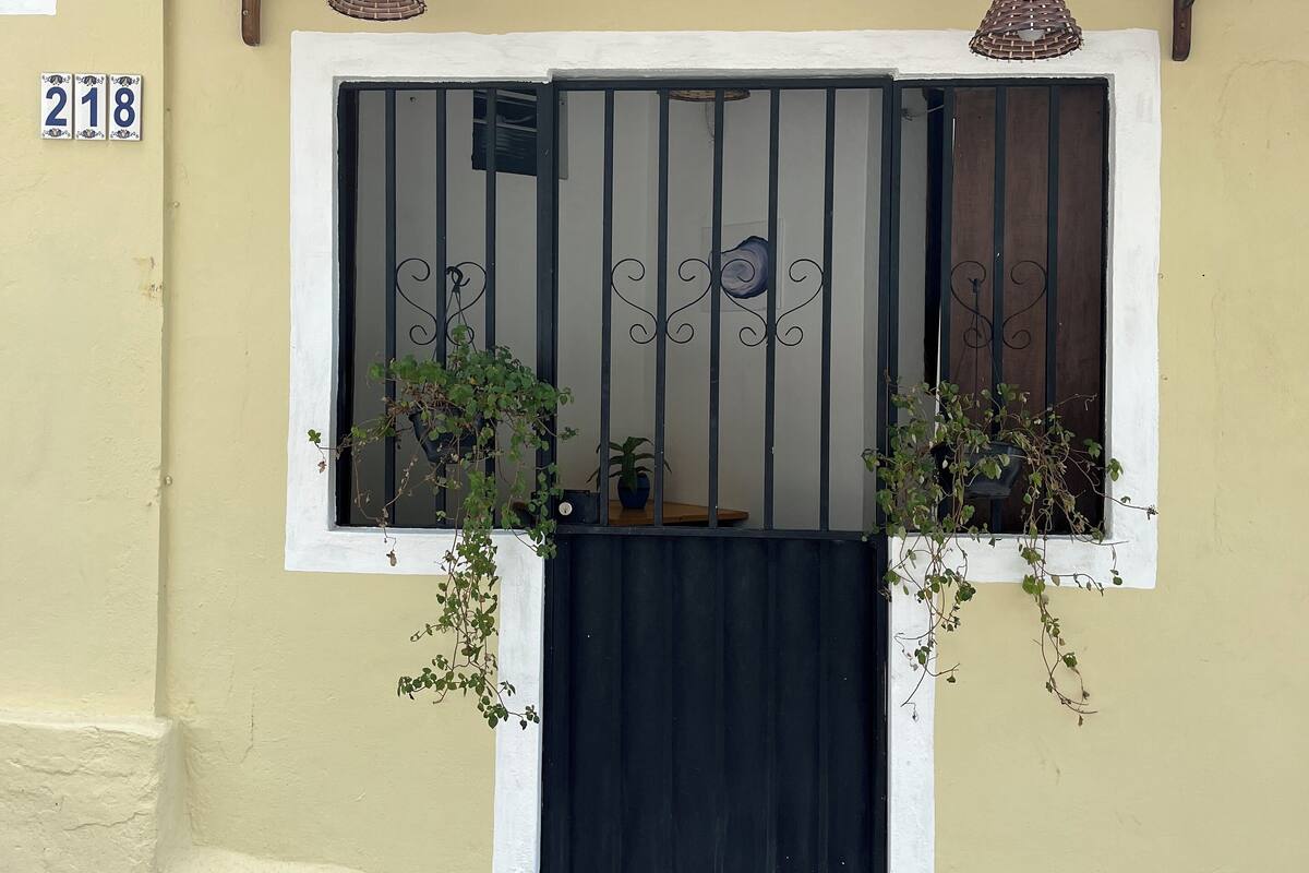 A building with a beige facade, a black gate with decorative bars, and a number '218' sign.