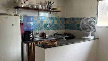 Una cucina con frigorifero, macchina del caffè, dispenser di acqua e ventilatore.
