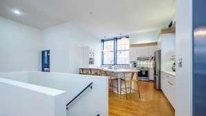 A modern kitchen with a central island, wooden flooring, and a view of the living area.