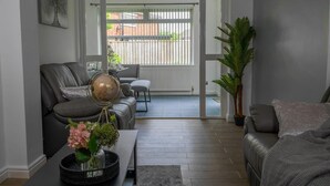 Una sala de estar moderna con un sofá de cuero, una mesa de centro con un globo terráqueo y flores, y vistas a un balcón a través de una puerta de vidrio.