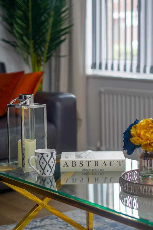 A glass coffee table with a book titled "ABSTRACT" and a decorative candle.