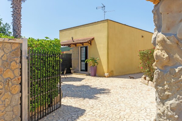 A stone gate, a yellow building with a tiled roof, and a stone wall.