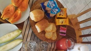 A dining table with a variety of food items including bread, cheese, and vegetables. - Vila Malie Milagres (São Miguel dos Milagres)