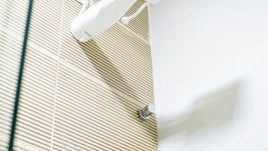 A shower with a white handheld showerhead and a wall-mounted control panel. - Vila Malie Milagres (São Miguel dos Milagres)
