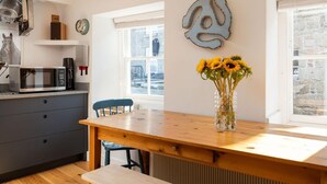 Una cocina moderna con una mesa de madera, un jarrón con girasoles y un gran elemento decorativo en la pared.