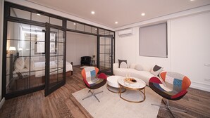 A modern living room with a glass partition, a sofa, two chairs, and a round coffee table. - 2-bedroom luxury apartment in the center of Yerevan by Sweet Home (Yerevan)