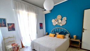 A bedroom with a bed, a chair, a bedside table, a wall with decorative items, and a door.