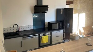 A modern kitchen with a black stove, microwave, and refrigerator, a wooden countertop, and a yellow towel hanging on the oven handle. - House Air conditioning in the countryside Vouvray (Vouvray)