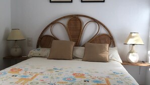 Un dormitorio con cama, dos mesitas de noche, dos lámparas y dos cuadros en la pared.