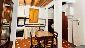 A compact kitchen with wooden cabinets, a dining table, and a tiled floor. - Best Guelfa Affittacamere (Florence)