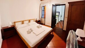A bedroom with a wooden bed, a nightstand, a fan, and a wardrobe. - Best Guelfa Affittacamere (Florence)