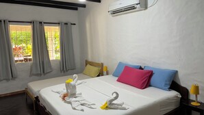 Habitació d'hotel amb llit, almoines, una taula de nit, aire condicionat i una finestra amb cortines.