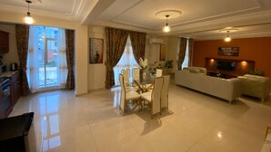 A spacious living room with a dining area, a sofa, and a TV. - Résidence hôtelière MEDOM Palace, Bastos (Yaoundé)