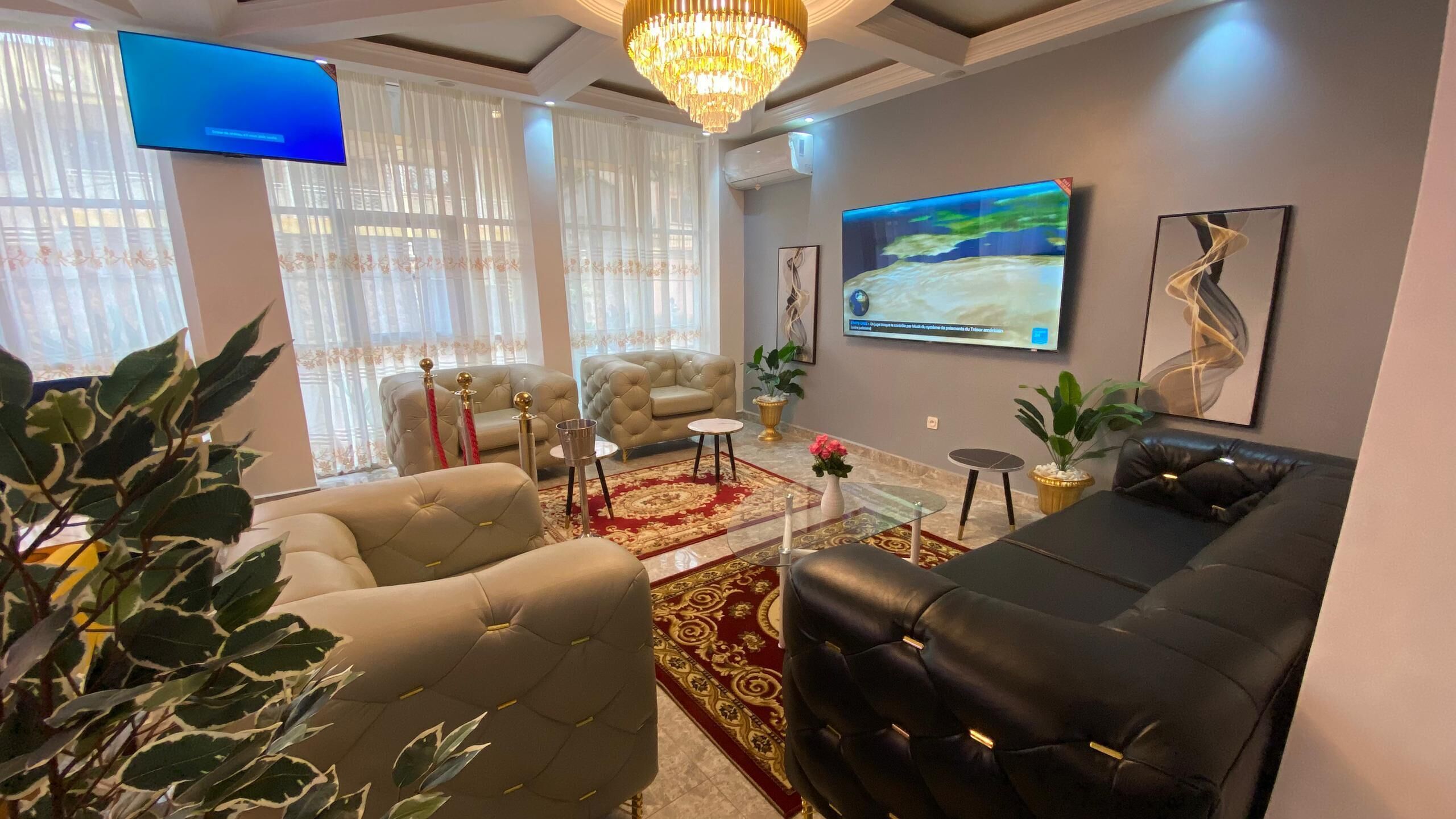 Un salon moderne doté d’un grand téléviseur, de sièges confortables et de plantes décoratives.