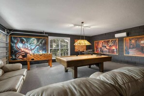 Una mesa de billar en una habitación con un cuadro grande de pulpo, una mesa de madera y una lámpara colgante.