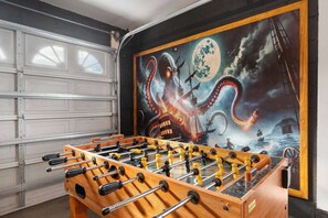 Una mesa de fútbol de mesa en un garaje con un mural de temática marina en la pared.