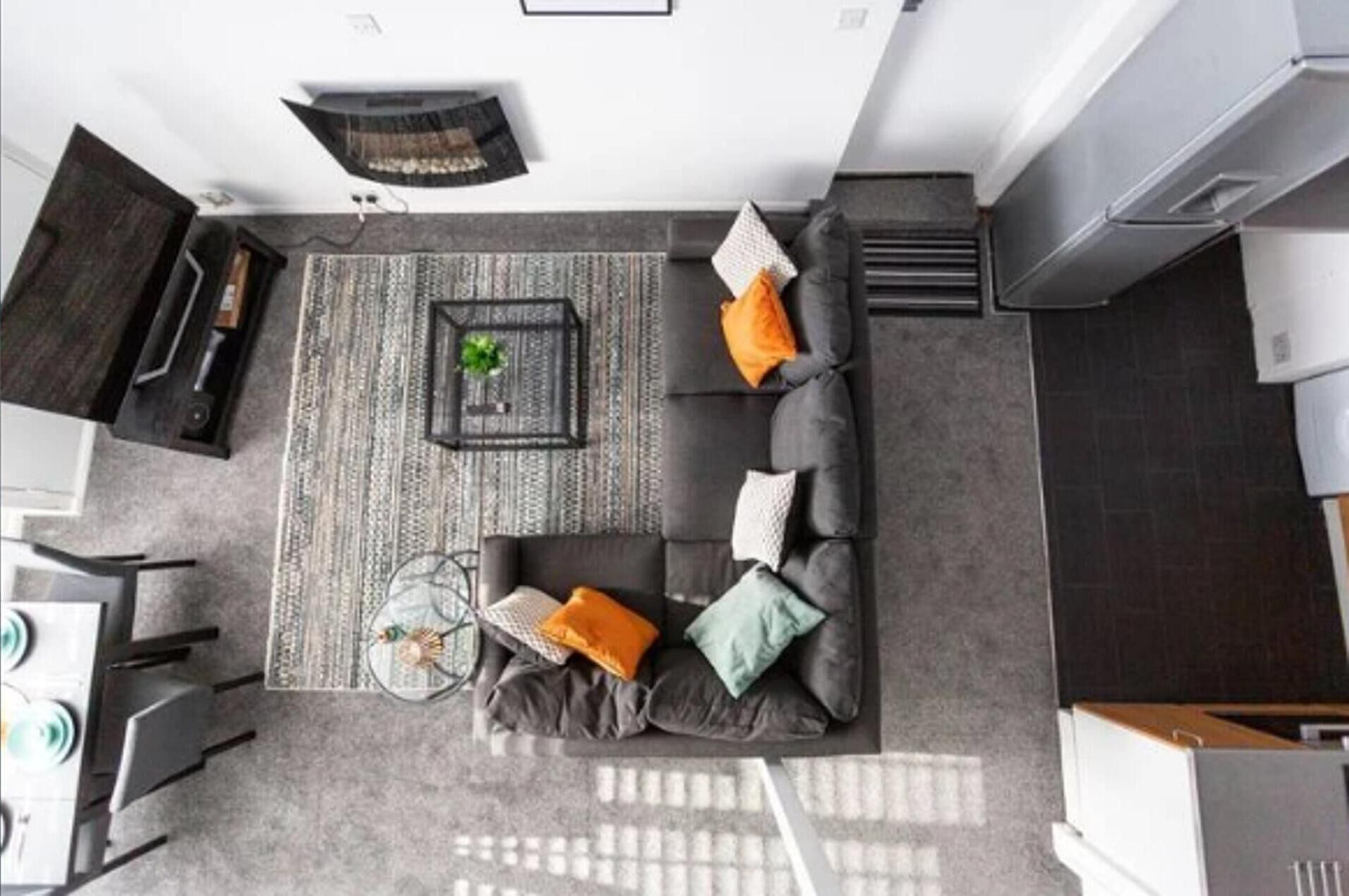 Un salon moderne avec un canapé gris, une table basse et un tapis à motifs.