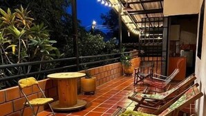 An outdoor patio area with tiled flooring, wooden chairs, a round table, and string lights. - Twin Room - 2 single beds (Jagua)
