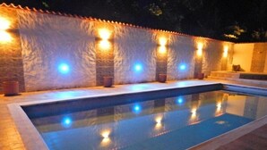 A swimming pool with a stone wall and lights along the edge. - Twin Room - 2 single beds (Jagua)