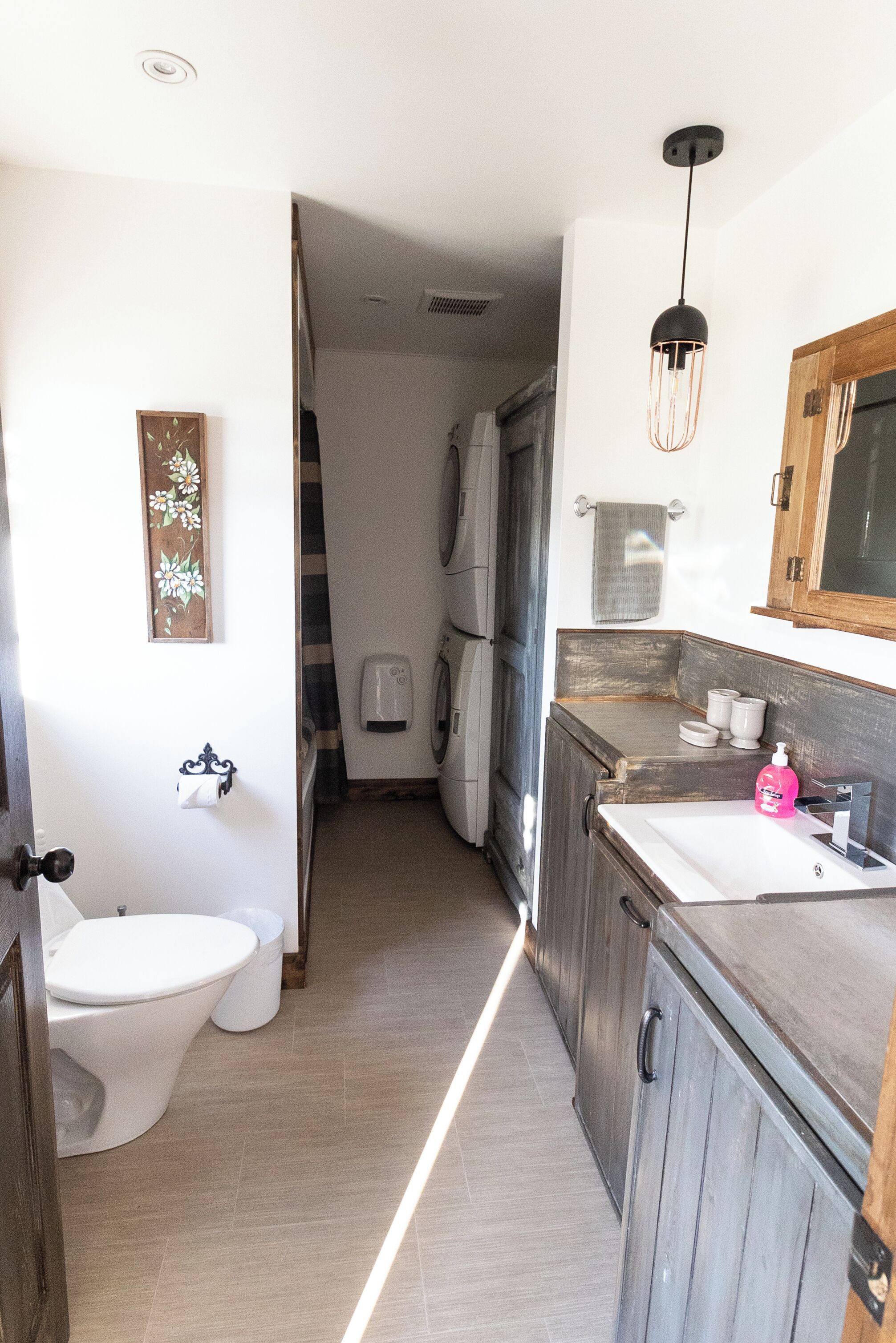 A narrow hallway with a toilet, sink, and cabinets.