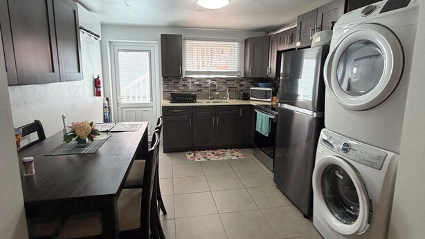 A compact kitchen with a dining area, a washing machine, and a microwave. - Charming 2-bedroom apartment with WiFi and AC in Devonshire (Devonshire)