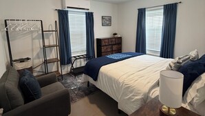 A bedroom with a bed, a desk, a chair, a wardrobe, and a radiator. - Charming 2-bedroom apartment with WiFi and AC in Devonshire (Devonshire)