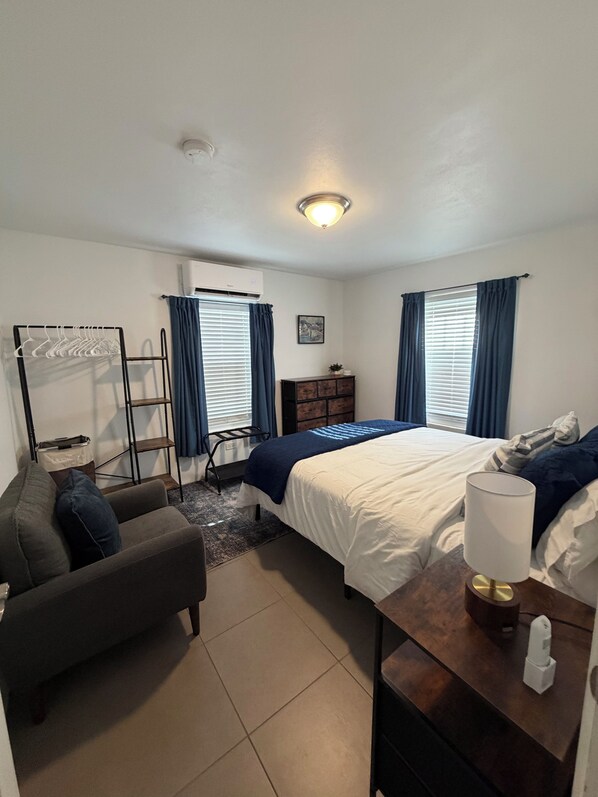 A bedroom with a bed, a desk, a chair, a wardrobe, and a radiator. - Charming 2-bedroom apartment with WiFi and AC in Devonshire (Devonshire)