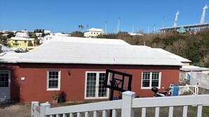 A red building with a white fence in front, a clear blue sky, and a distant stadium. - Charming 2-bedroom apartment with WiFi and AC in Devonshire (Devonshire)
