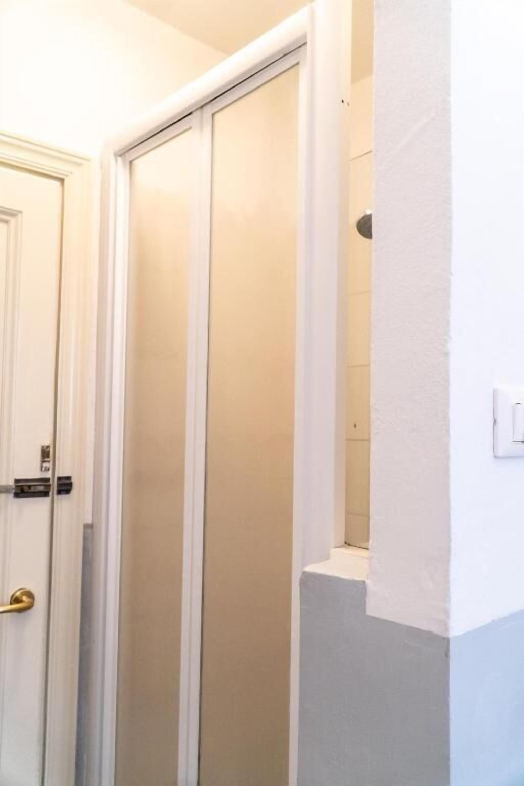 A hallway with a white door, a white wall, and a light switch.