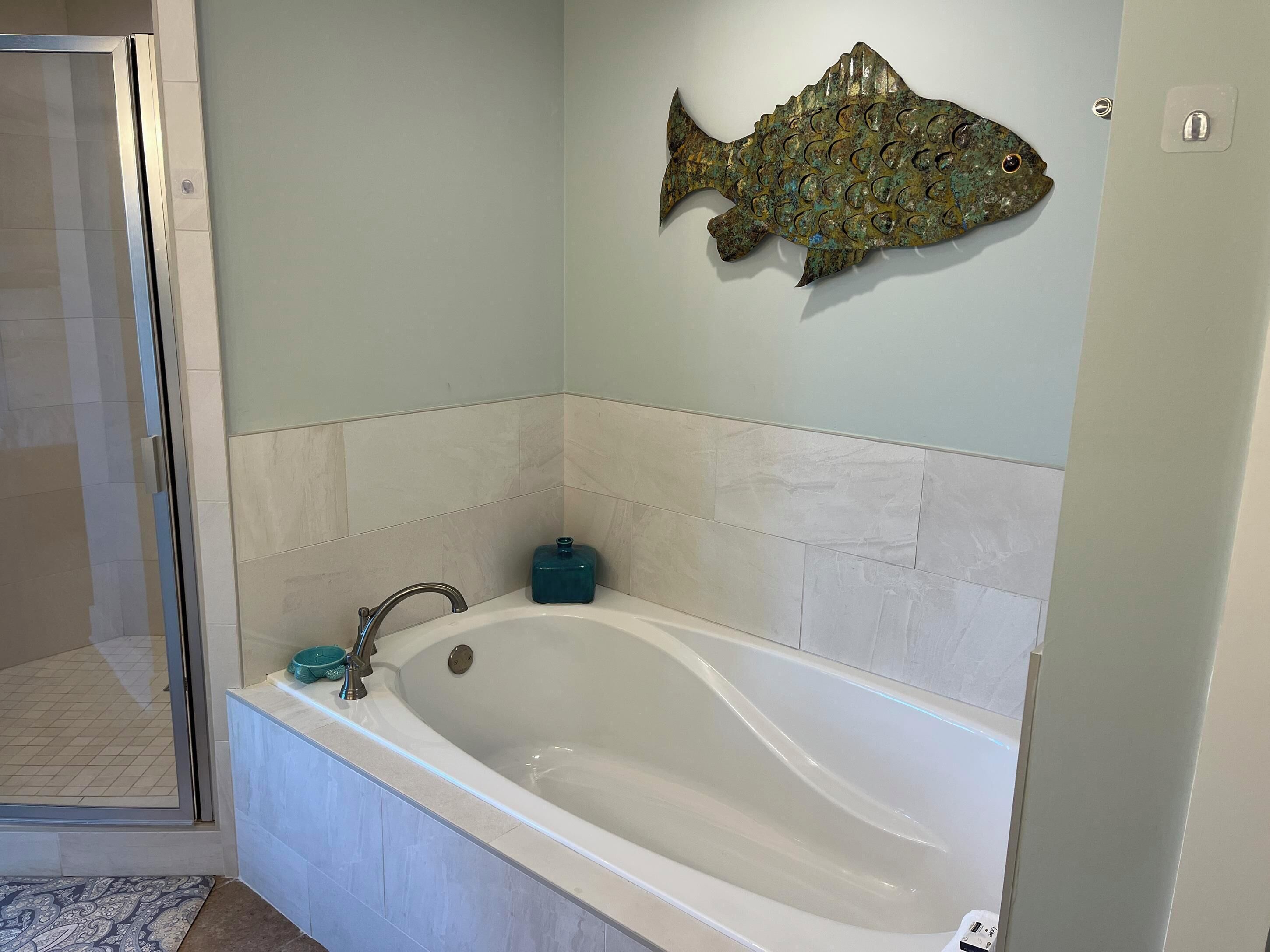 A bathroom with a bathtub, a shower, and a wall-mounted fish decoration.