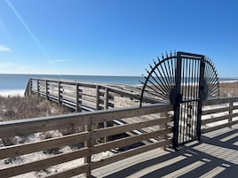 Una pasarela de madera que conduce a una playa con una reja metálica.