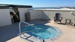 Una piscina en la azotea con una escalera de metal, una silla y una mesa.