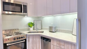 Een moderne keuken met roestvrijstalen apparatuur, een inbouwvaatwasser en een magnetron boven het fornuis.