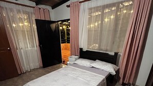 Une chambre à coucher avec un lit, des rideaux et une vue sur l’extérieur.