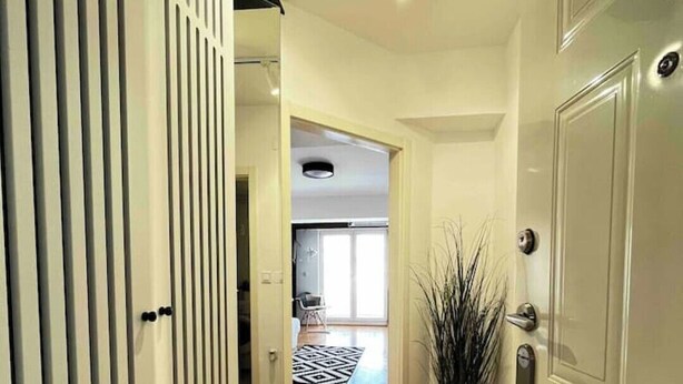 Un couloir avec un sol à motifs en chevrons, une porte blanche sur la droite et une cloison blanche sur la gauche.