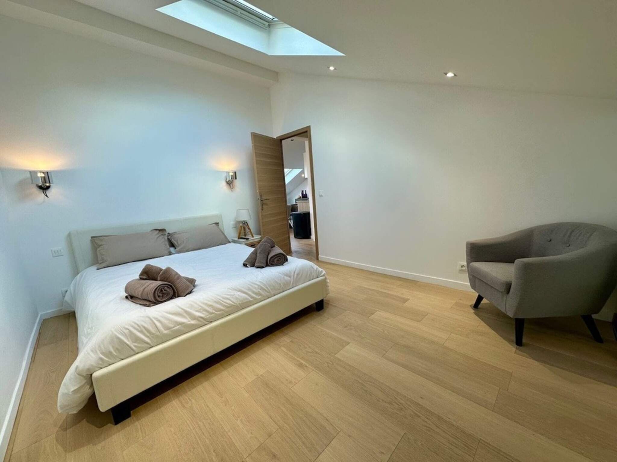Une chambre à coucher moderne avec un lit, une chaise, une lucarne et un miroir.