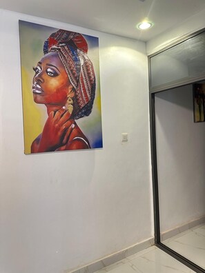 Un couloir avec un grand tableau accroché au mur, une porte et un sol carrelé.