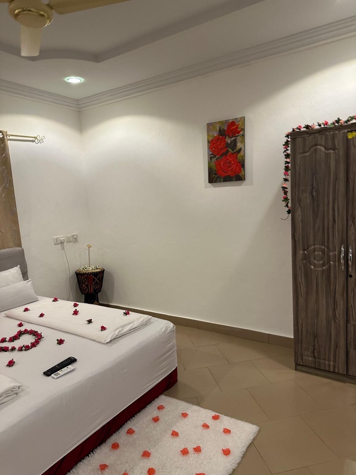 A bedroom with a bed, a nightstand, a painting, and a wardrobe.