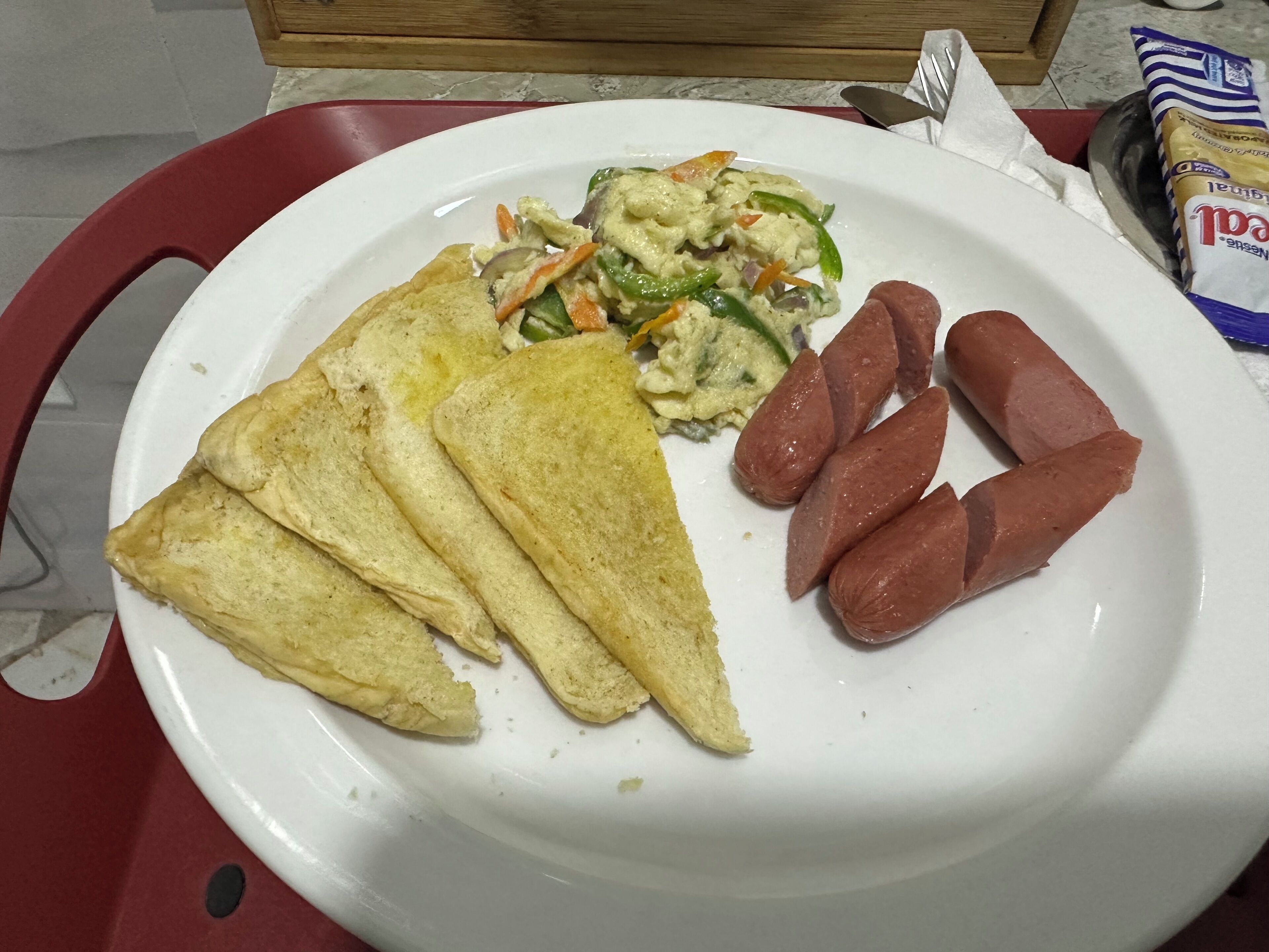 A plate with toast, sausages, and a vegetable salad.