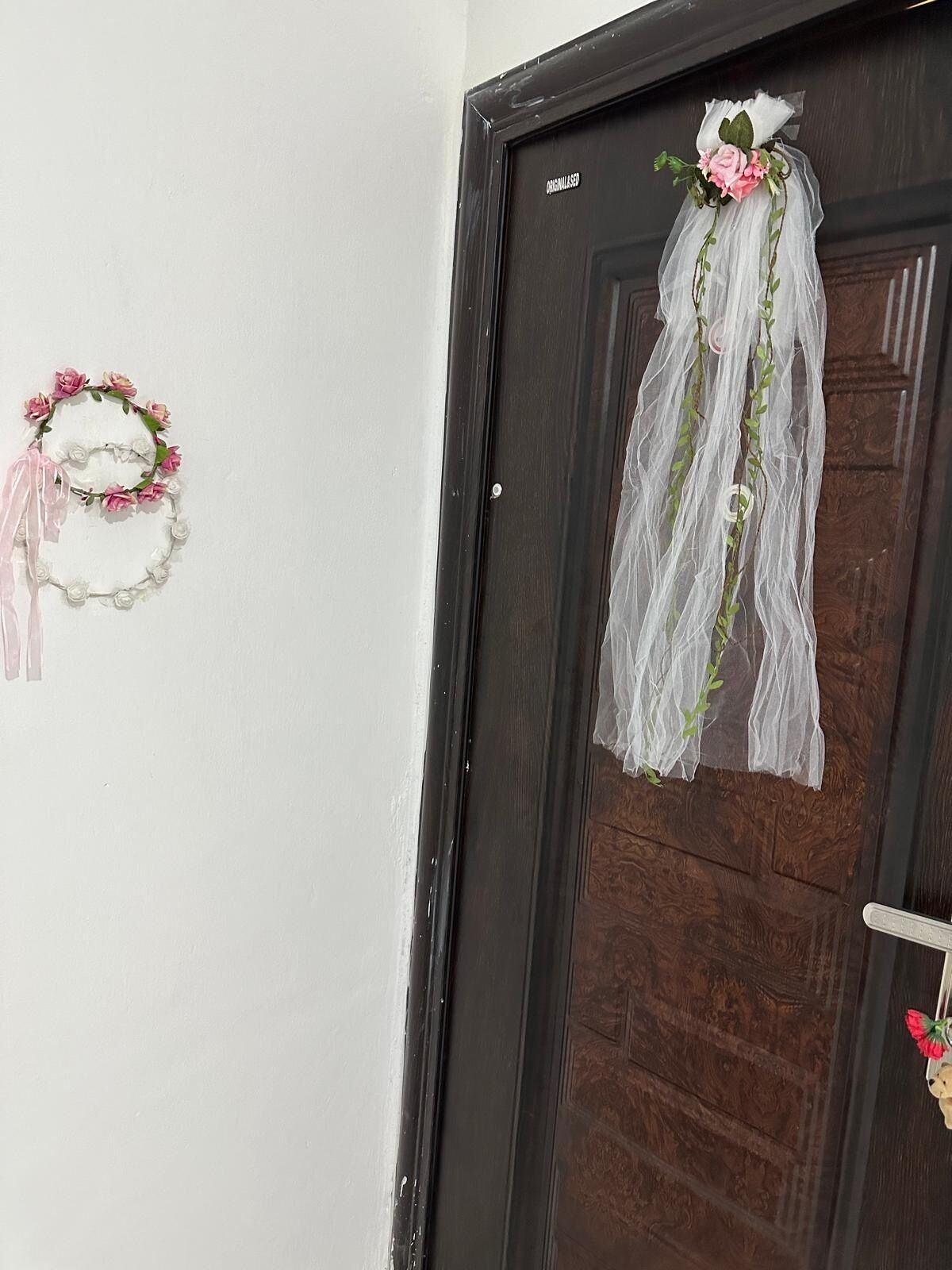 A door with a white wreath and a white floral arrangement on the wall.