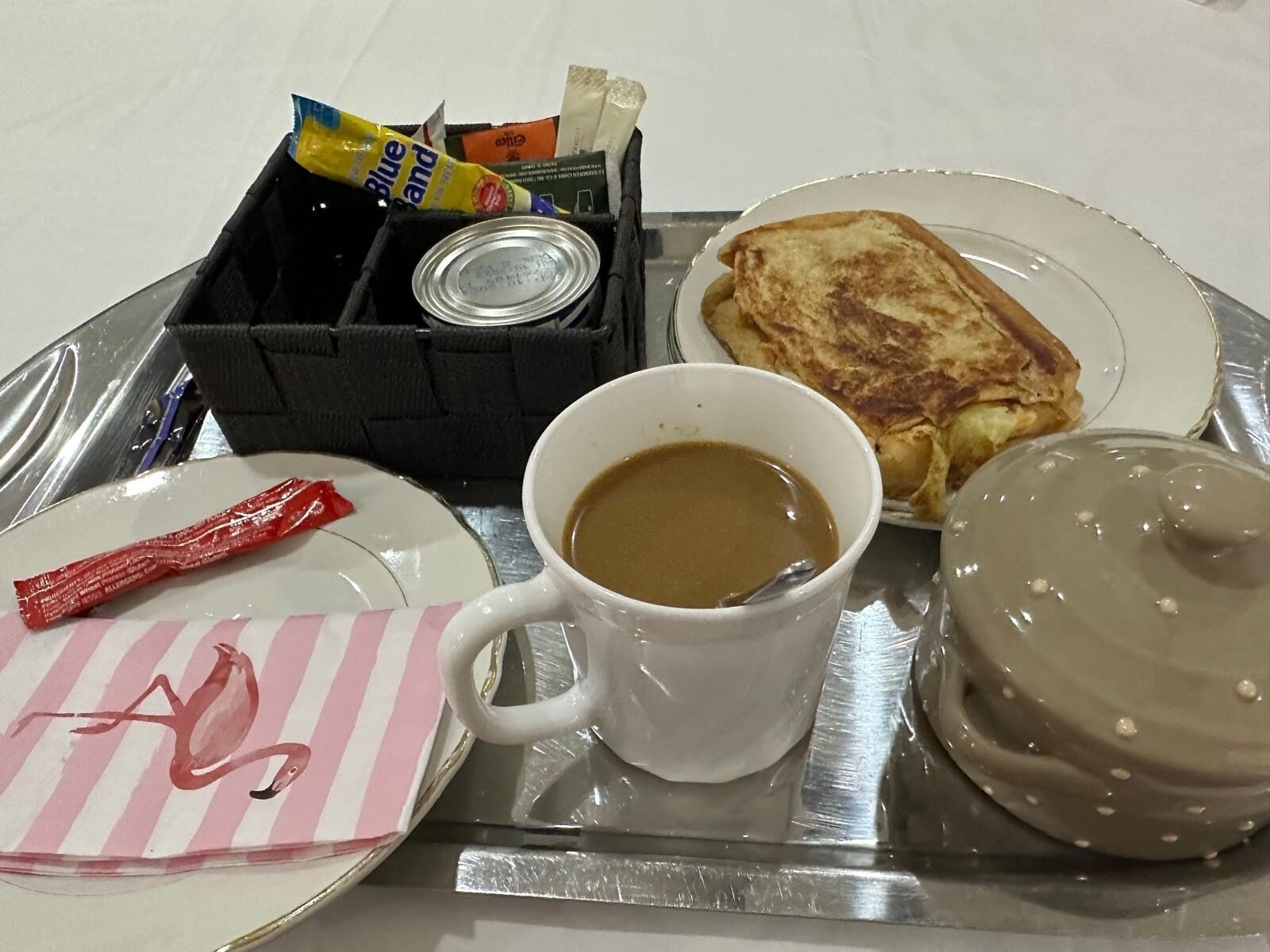 A tray with a plate of toast, a mug of coffee, a donut, and a packet of gum.