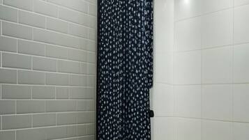 Een badkamer met toilet, douchegordijn en witte betegelde wanden.